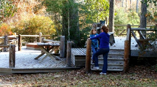 Outdoor deck with hot tub in back surrounded by Big Thicket